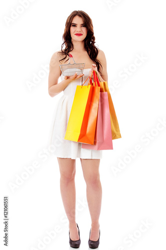 Young woman holding small empty shopping basket and shopping bags