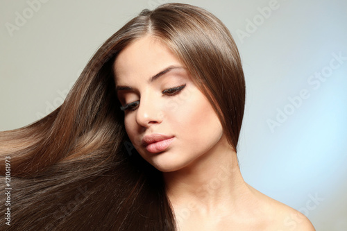 Young woman with healthy hair on light background