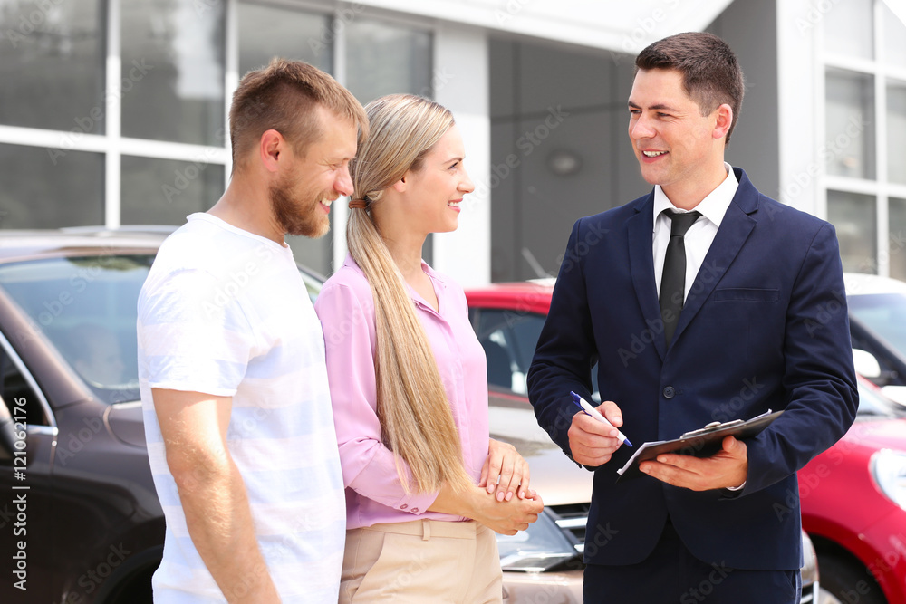 Young couple buying car at dealership center Young couple buying car at dealership center