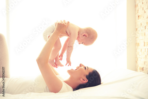 Mother and baby playing on bed