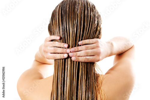 Woman applying hair conditioner. Isolated on white.