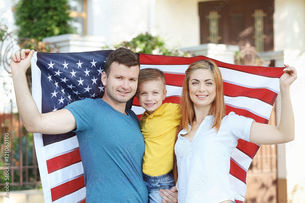 Fototapeta premium Happy family with American flag in the yard