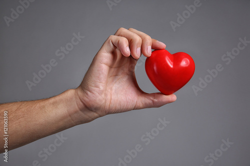 Fototapeta Naklejka Na Ścianę i Meble -  Male hand holding red heart on grey background