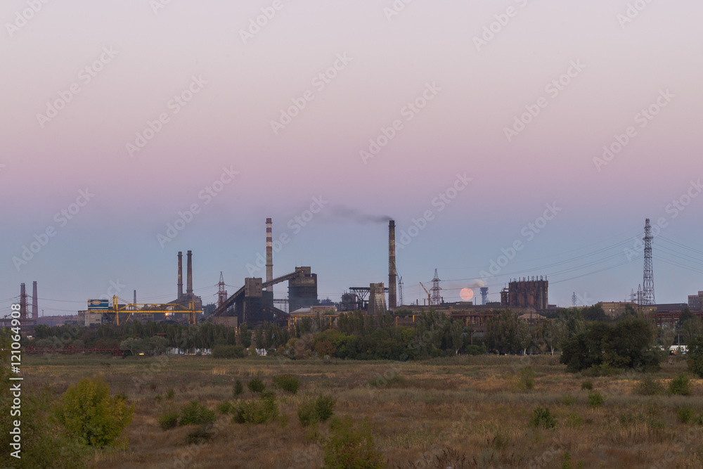 Picture of metallurgical plant and its Smoking chimneys in the background of clear sky