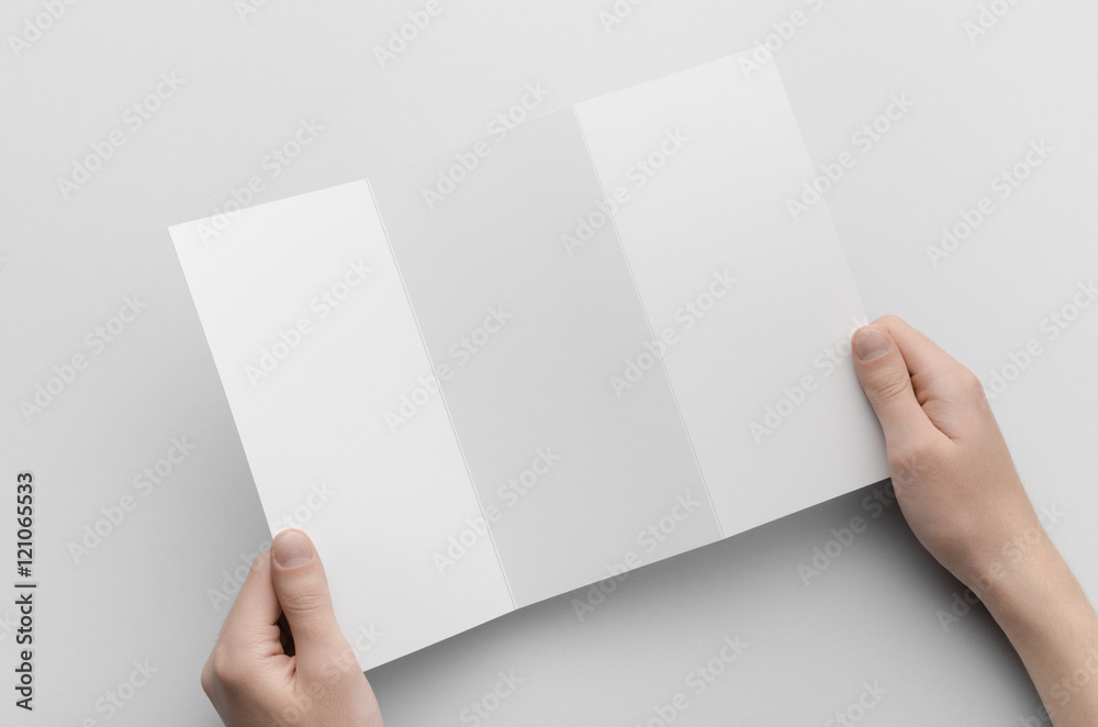 A4 Z-Fold Brochure Mock-Up - Male hands holding a blank tri-fold on a gray background. A4 Z-Fold Brochure Mock-Up - Male hands holding a blank tri-fold on a gray background.