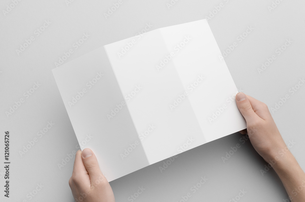 A4 Tri-Fold Brochure Mock-Up - Male hands holding a blank tri-fold on a gray background. A4 Tri-Fold Brochure Mock-Up - Male hands holding a blank tri-fold on a gray background.