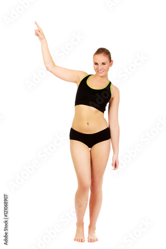 Young athletic woman pointing for copyspace or something