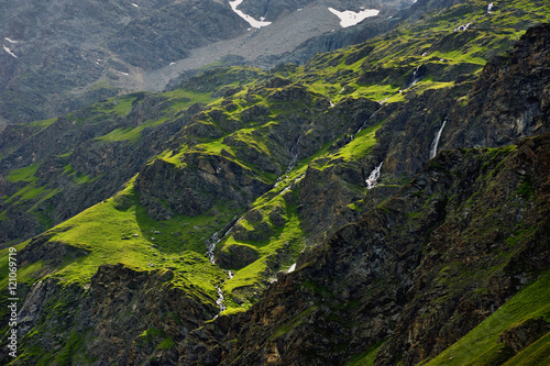 small waterfalls on summer green hills in Alps Valley