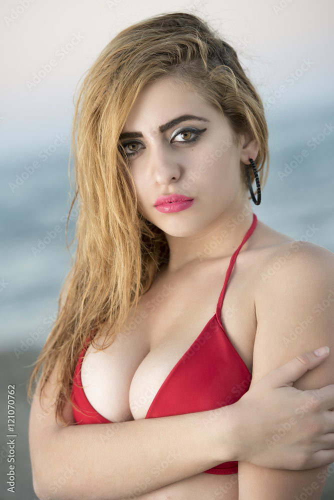 Blond woman with desired curved body wear two pieces bikini, ocean as background. Photo taken late afternoon Blond woman with desired curved body wear two pieces bikini, ocean as background. Photo taken late afternoon