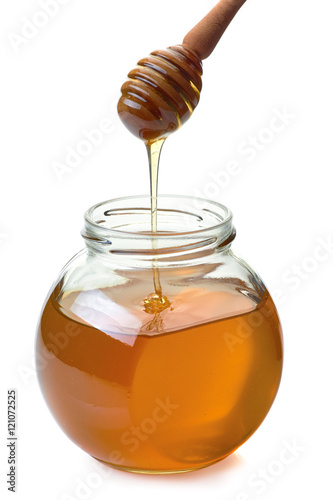 Jar with dripper an flowing honey on white