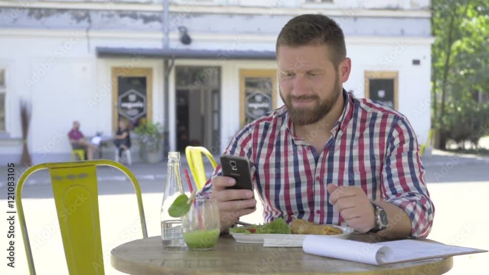 Young man browsing smartphone, during lunch. He is sitting at the table in cafe. He is young and has beard. Man is dressed in checkered shirt. Slider and pan shot.
Young man browsing smartphone, during lunch. He is sitting at the table in cafe. He is young and has beard. Man is dressed in checkered shirt. Slider and pan shot.