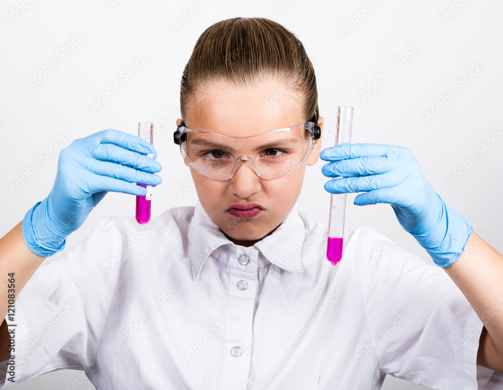 close-up little girl in a medical dress. Attentive schoolgirl conducting a chemistry experiment at elementary science class. close-up little girl in a medical dress. Attentive schoolgirl conducting a chemistry experiment at elementary science class.