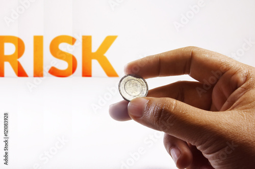 Hand Holding a Coin with blurred word : Risk on the white background