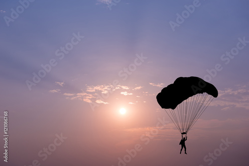 Silhouette of parachute on sunset background