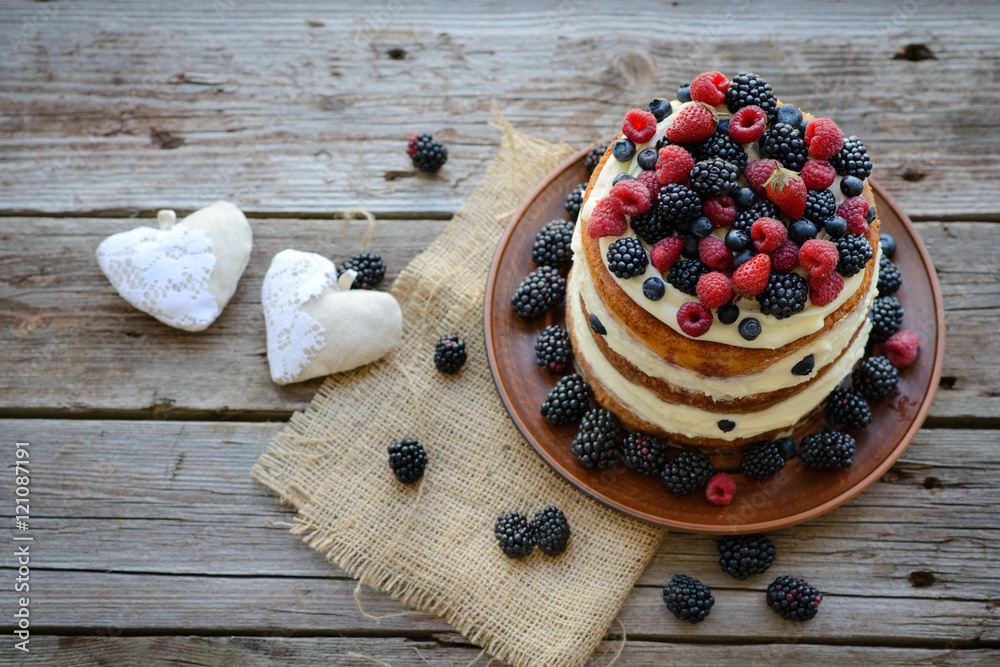 Tasty cake with strawberry, raspberry and blackberry on a wooden table Tasty cake with strawberry, raspberry and blackberry on a wooden table