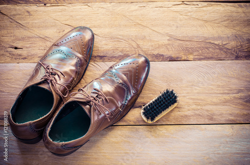 Leather shoes, brushes, placed on a wooden floor.