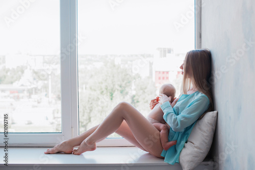 Baby in a tender embrace of yong mother at the windowstill,motherhood,family