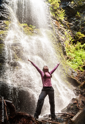 Happy woman standing in front of waterfall
