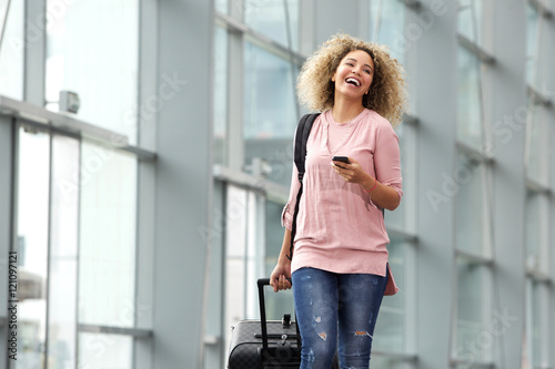Female traveler holding cellphone and suitcase
