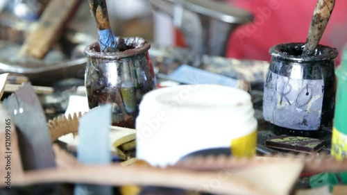 Calzolaio al Lavoro nella sua bottega artigianale. Mano che cerca tra gli attrezzi da lavoro.  photo