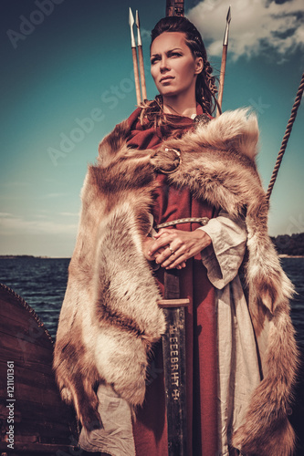 Viking woman with sword and shield standing on Drakkar. photo