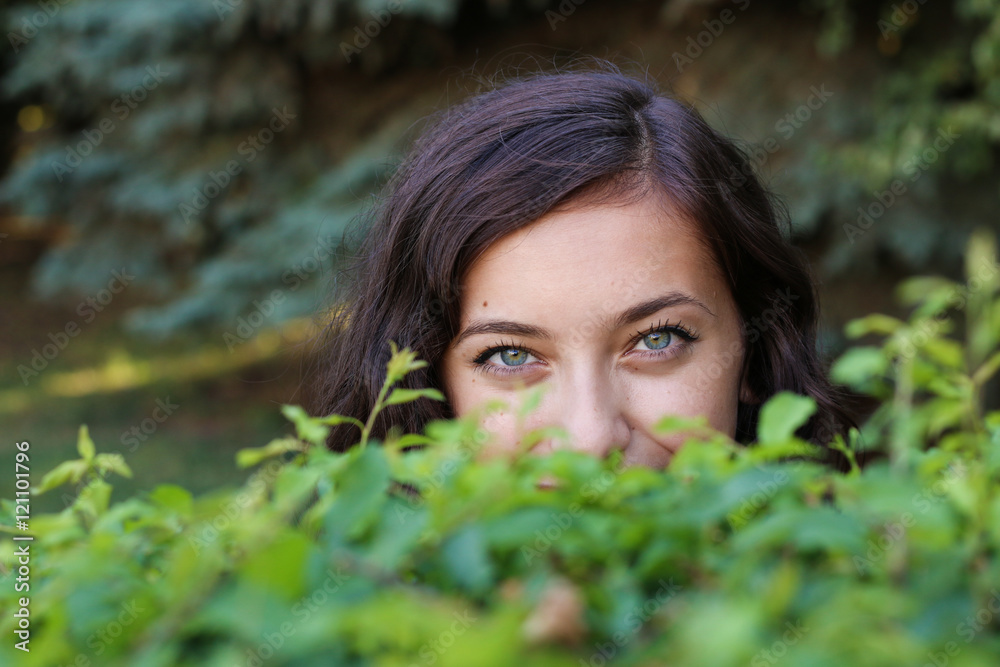 Smiling glance from a woman behind the bushes Smiling glance from a woman behind the bushes