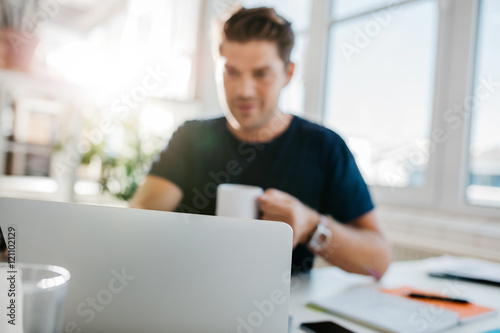 Laptop on table with man sitting by