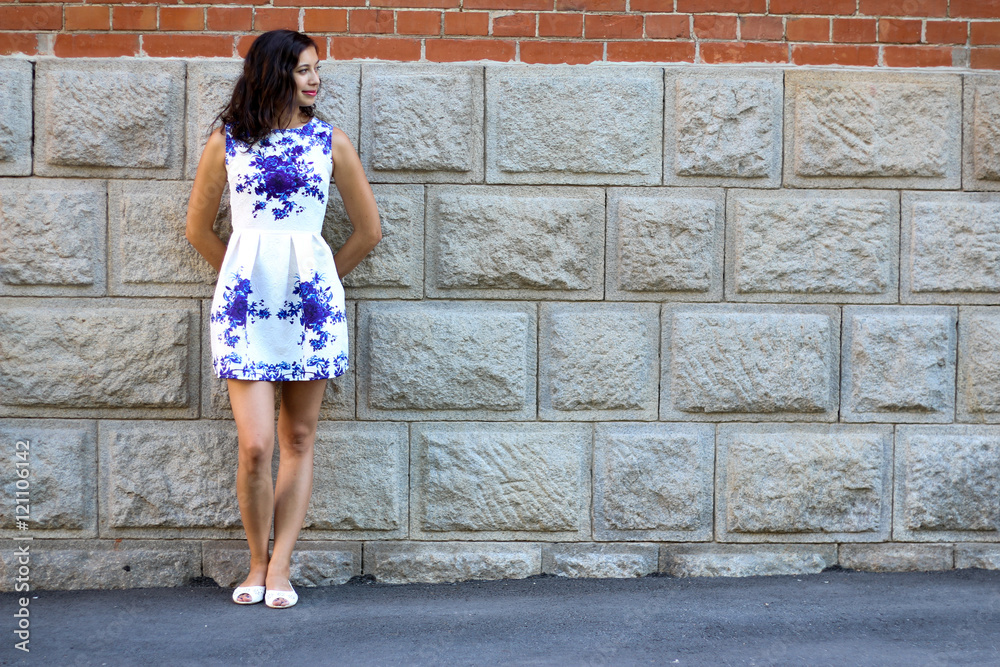 Young girl in full-length poses near a brick wall Young girl in full-length poses near a brick wall