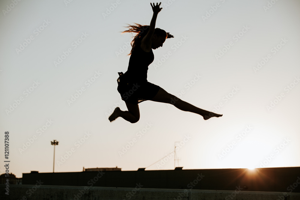 Woman performing dance and jumping in the air. Backlighting.