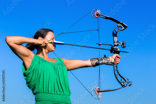 Young woman aiming arrow of compound bow photo