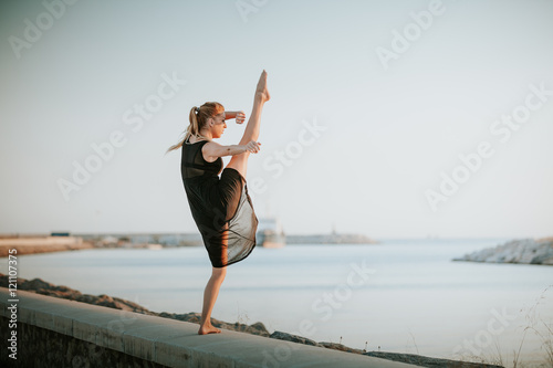 Dancer with one leg up, performing dance at seashore.