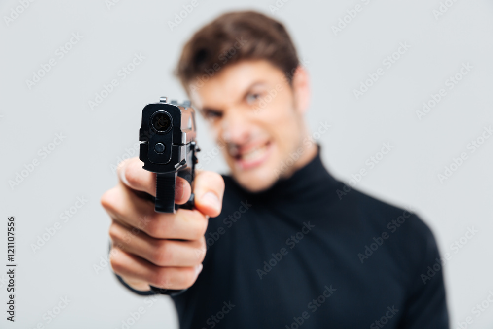 Closeup of angry young man pointing with gun on you Closeup of angry young man pointing with gun on you