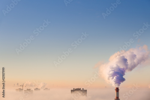 Smoking pipes of thermal power plant on sunset. White smoke and steam from a high chimney of a power plant against a bright blue sky. air pollution