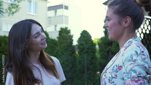 Two young women are talking and describing something to each other. Urban background
