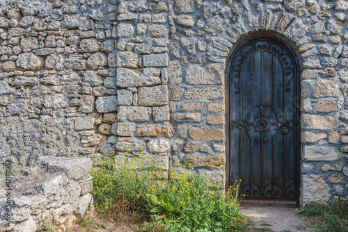 Heavy closed door on a stone wall of medieval fortress, made riveted wood © Irina Sokolovskaya