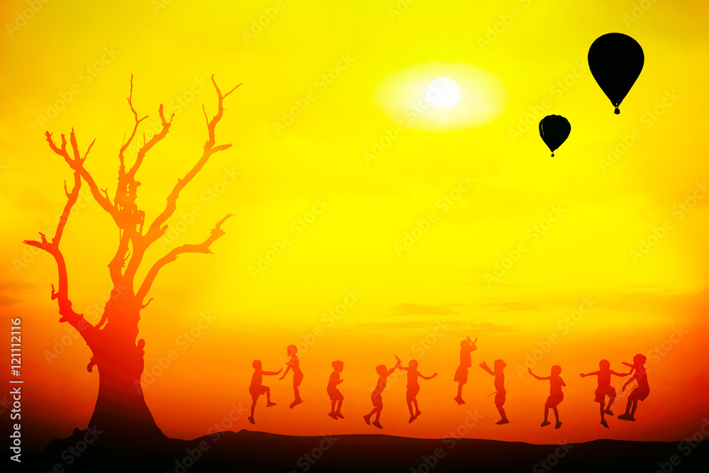 Silhouette of happy childrens jumping at sunset time