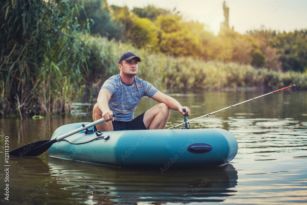 man fishing from the rubber boat on the pond man fishing from the rubber boat on the pond
