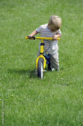Child boy riding on his first bike with a helmet. Bike without pedals. Child learning to ride and balance on his two wheeler bike with no pedals.