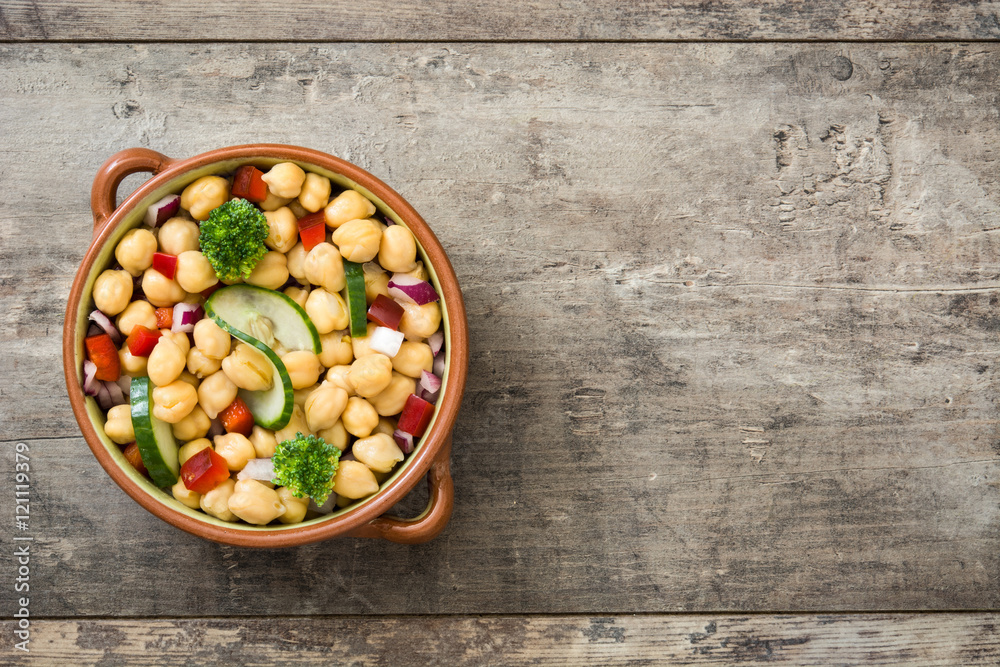 Chickpea salad in brown bowl on wooden background

