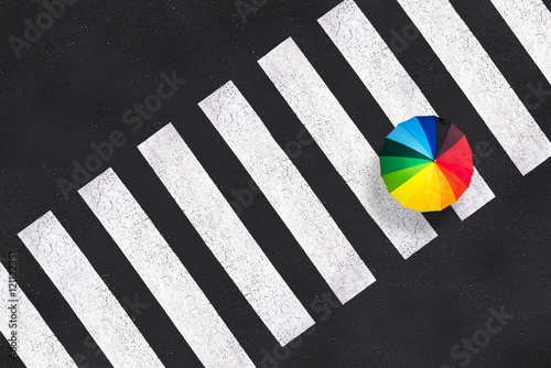 Obraz na plátne Top view of a rainbow umbrella on a pedestrian crosswalk