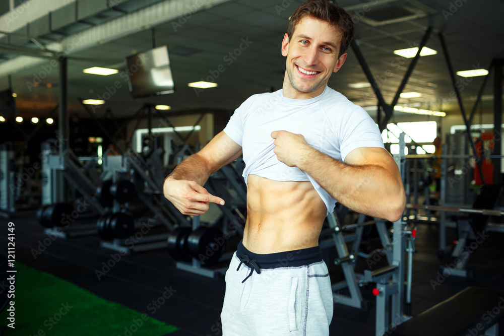 Athletic man showing abdominal muscles in gym Athletic man showing abdominal muscles in gym