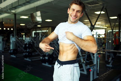 Athletic man showing abdominal muscles in gym