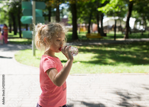 Little girl with bottle of mineral water  summer outdoor