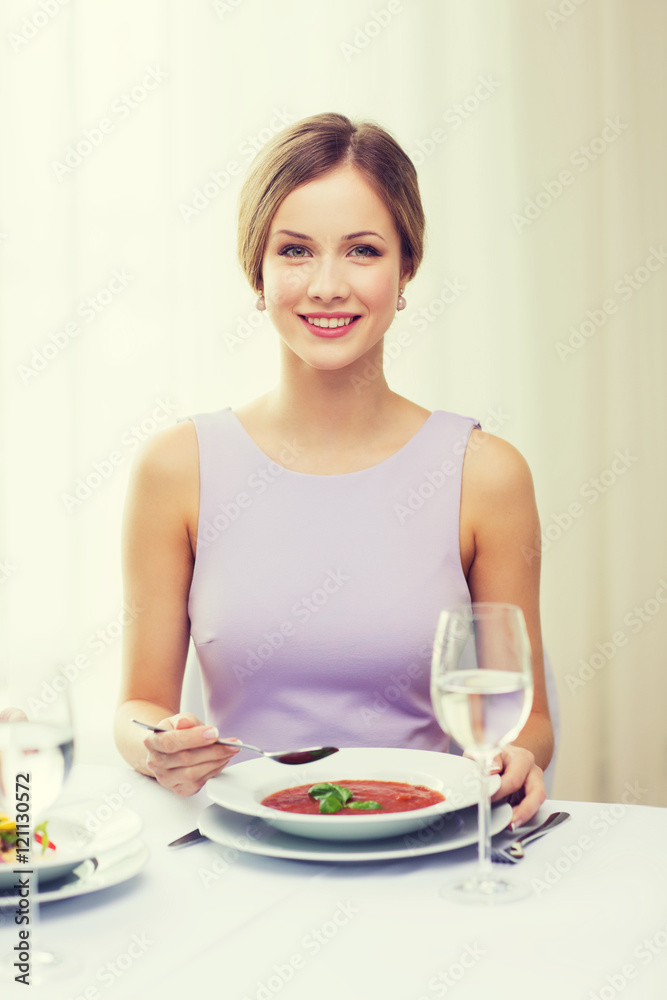 smiling young woman eating appetizer at restaurant smiling young woman eating appetizer at restaurant