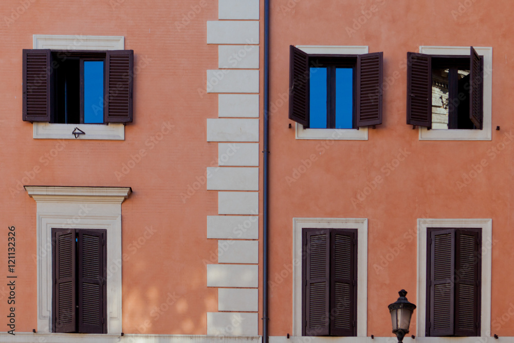 Peach building with windows hidden behind dark brown shutters Peach building with windows hidden behind dark brown shutters