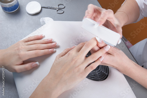 Manicure. Processing of extended nails by a whetstone photo