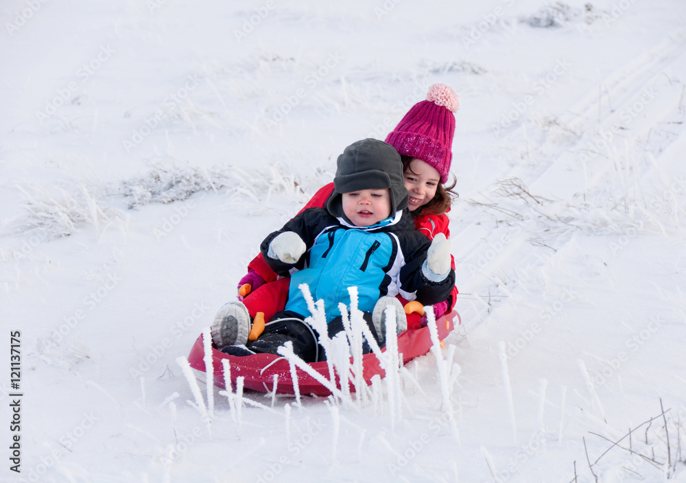 Two children sledding in winter