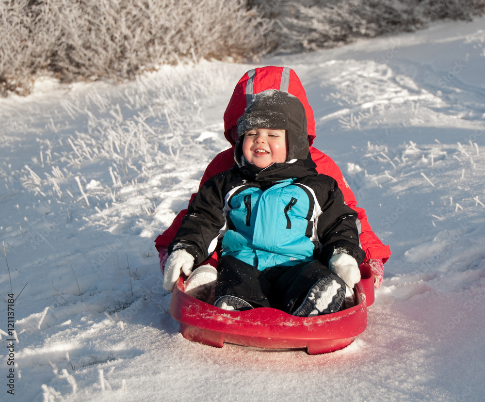 Two children sledding in winter Two children sledding in winter