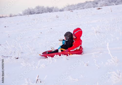 Two children sledding in winter