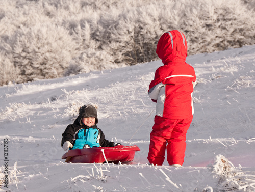 Two children sledding in winter